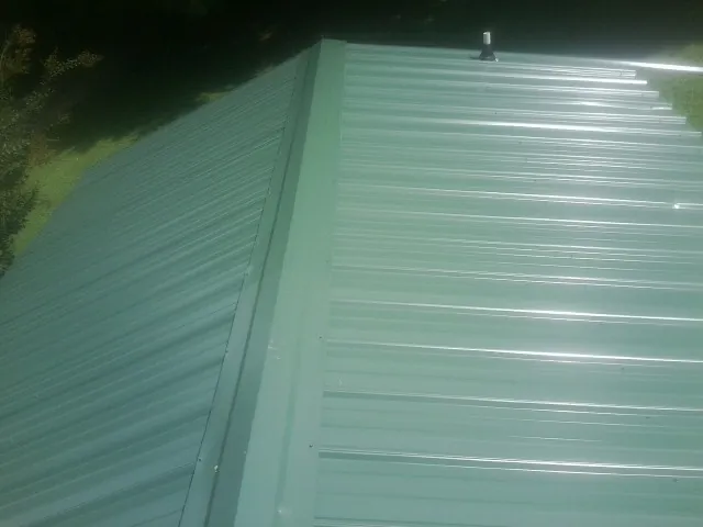New green metal panels meeting at the ridge of a roof — Flat Roof Repair work by our crew in Gordon